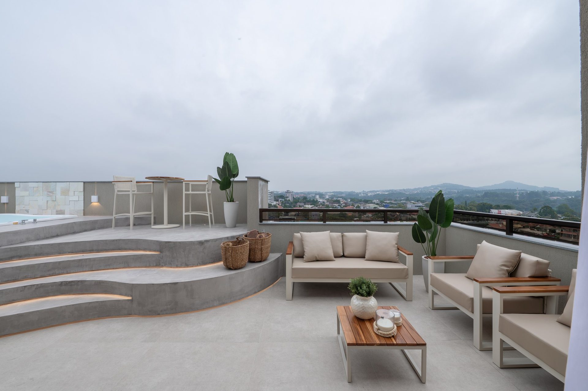 Varanda gourmet com sofás de área externa, mesa baixa de madeira e vista para a cidade